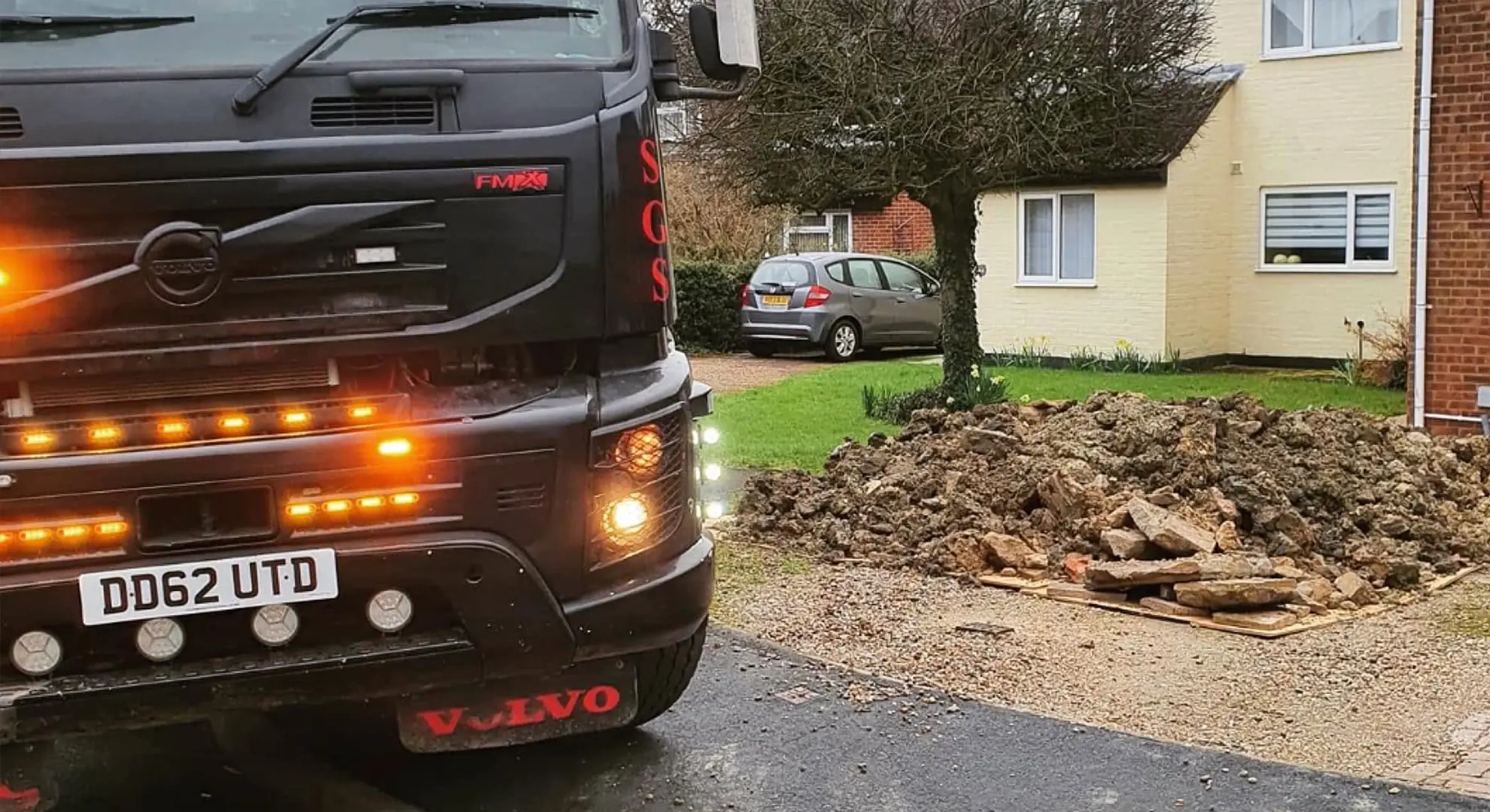 Sandy Grab Services lorry collecting a pile of rubble from a residential driveway